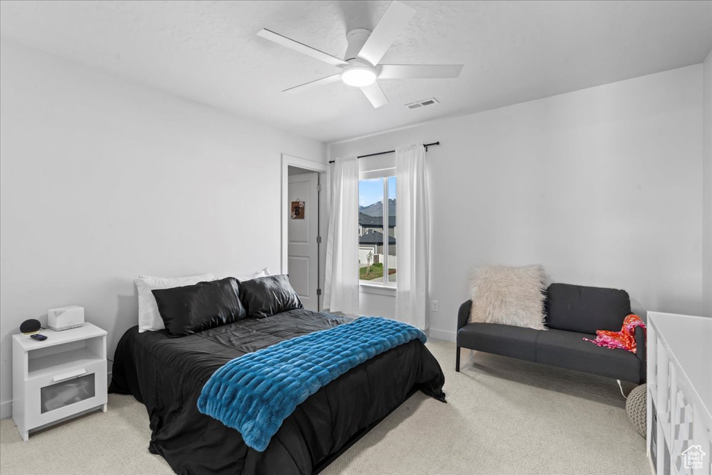 Bedroom featuring light colored carpet, ceiling fan, and baseboards