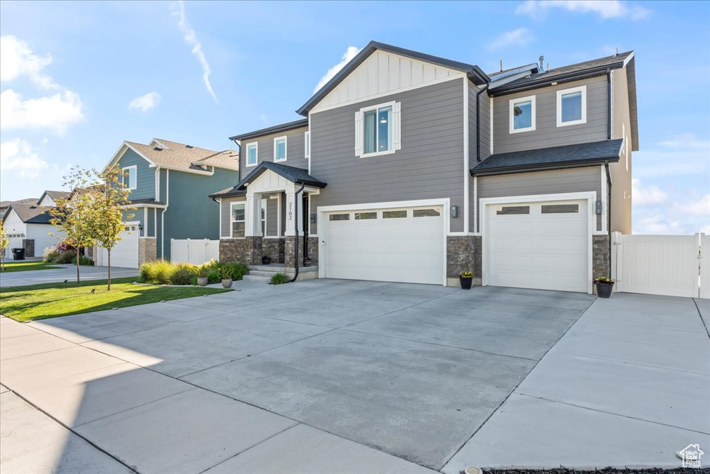 View of front of house with board and batten siding, a garage, concrete driveway, and stone siding