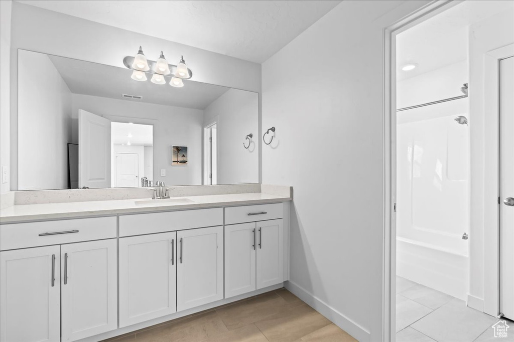 Bathroom with vanity, bathing tub / shower combination, tile patterned flooring, and baseboards