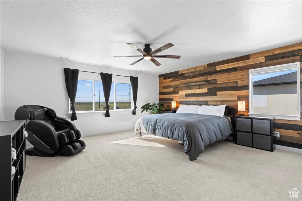 Bedroom featuring wooden walls, carpet, a textured ceiling, and a ceiling fan