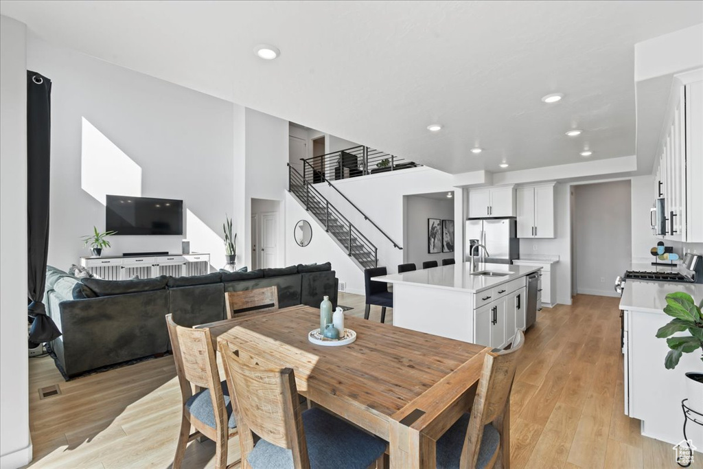 Dining space with stairs, light wood finished floors, and recessed lighting