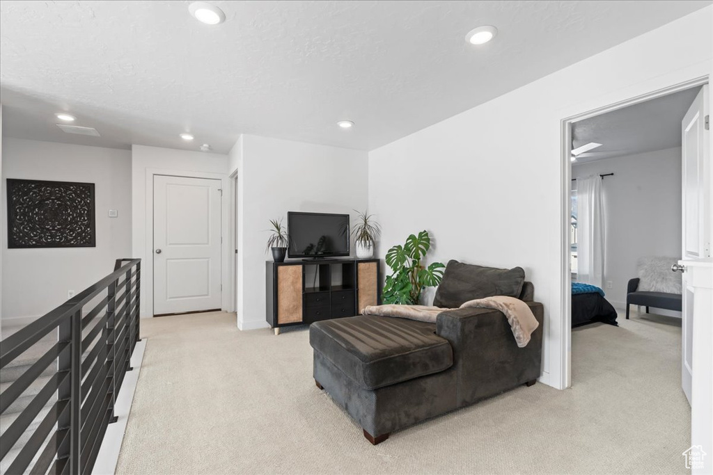 Living area with light carpet, recessed lighting, and baseboards