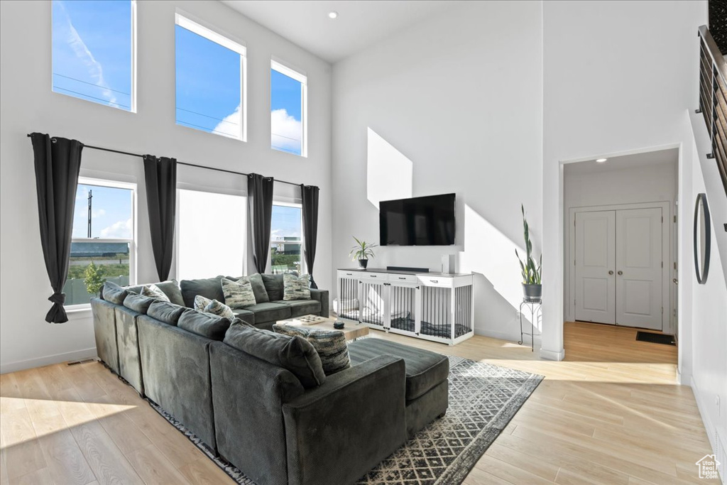 Living room with a towering ceiling, healthy amount of natural light, wood finished floors, and baseboards