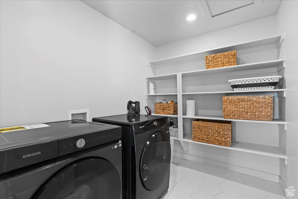 Washroom featuring washing machine and clothes dryer, tile patterned flooring, and attic access