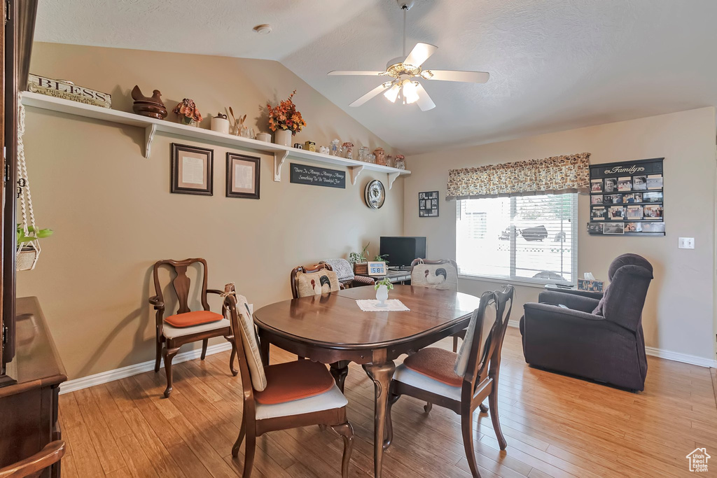 Dining space with lofted ceiling, a ceiling fan, light wood-type flooring, and baseboards
