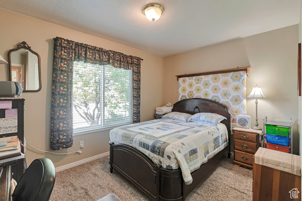Bedroom with light carpet, baseboards, and a textured ceiling