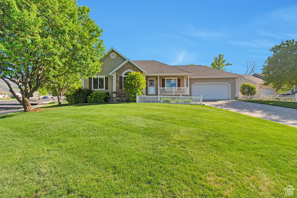 Ranch-style home with a garage, a porch, a front yard, concrete driveway, and stucco siding