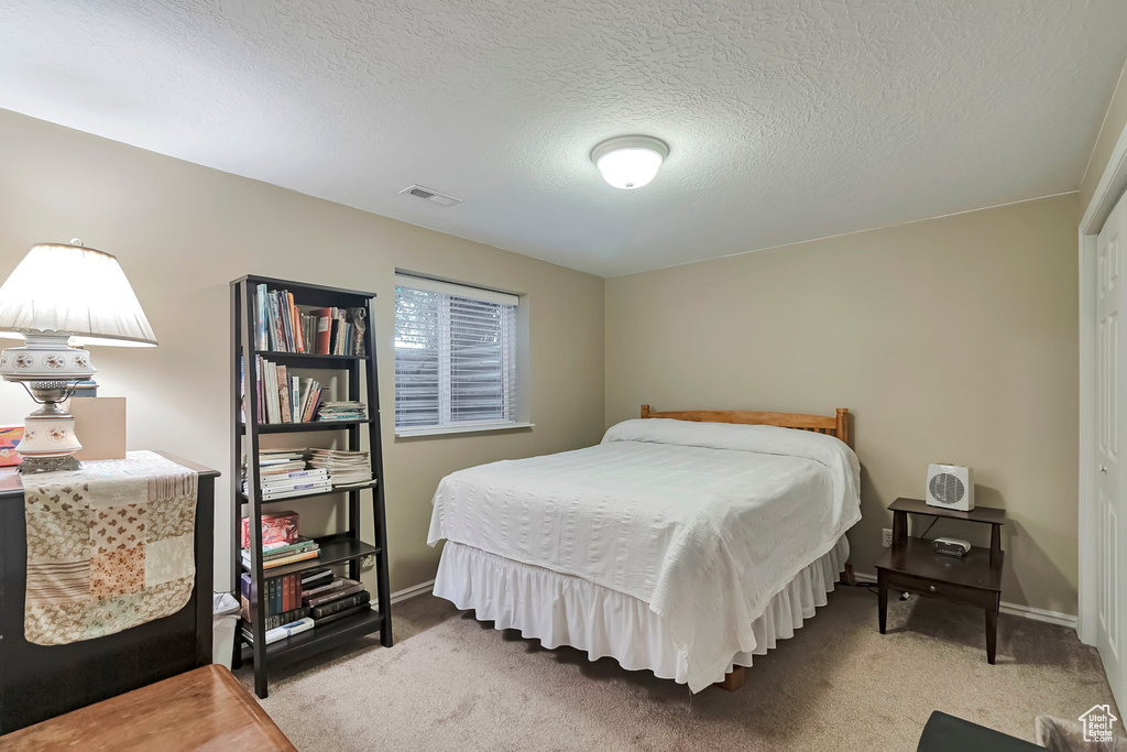Bedroom with carpet flooring, a textured ceiling, and baseboards