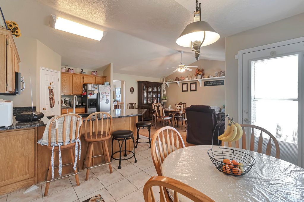 Dining space featuring a ceiling fan, light tile patterned floors, and lofted ceiling