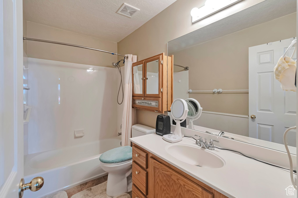 Bathroom featuring toilet, washtub / shower combination, vanity, and a textured ceiling