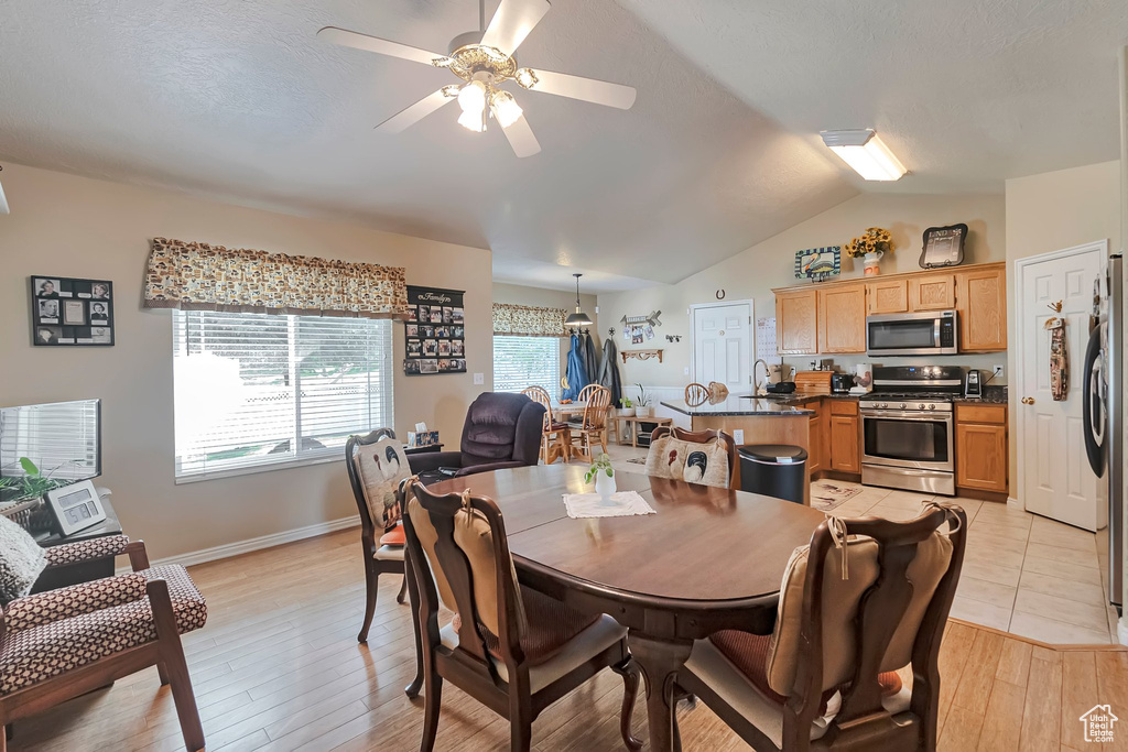 Dining area featuring a ceiling fan, lofted ceiling, light wood-style flooring, and baseboards