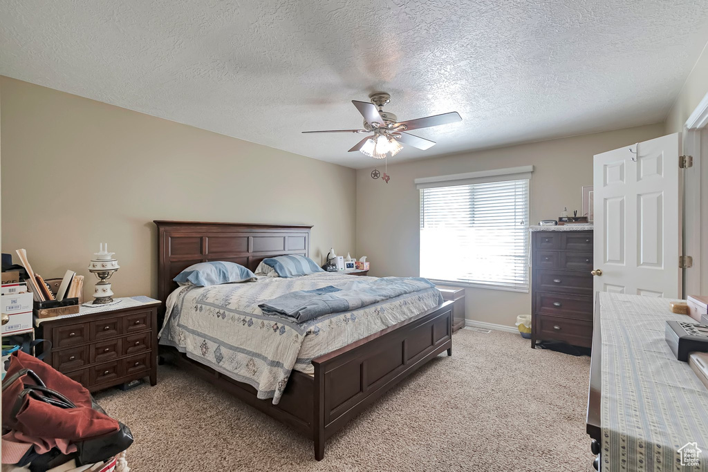 Bedroom featuring light colored carpet, a textured ceiling, ceiling fan, and baseboards