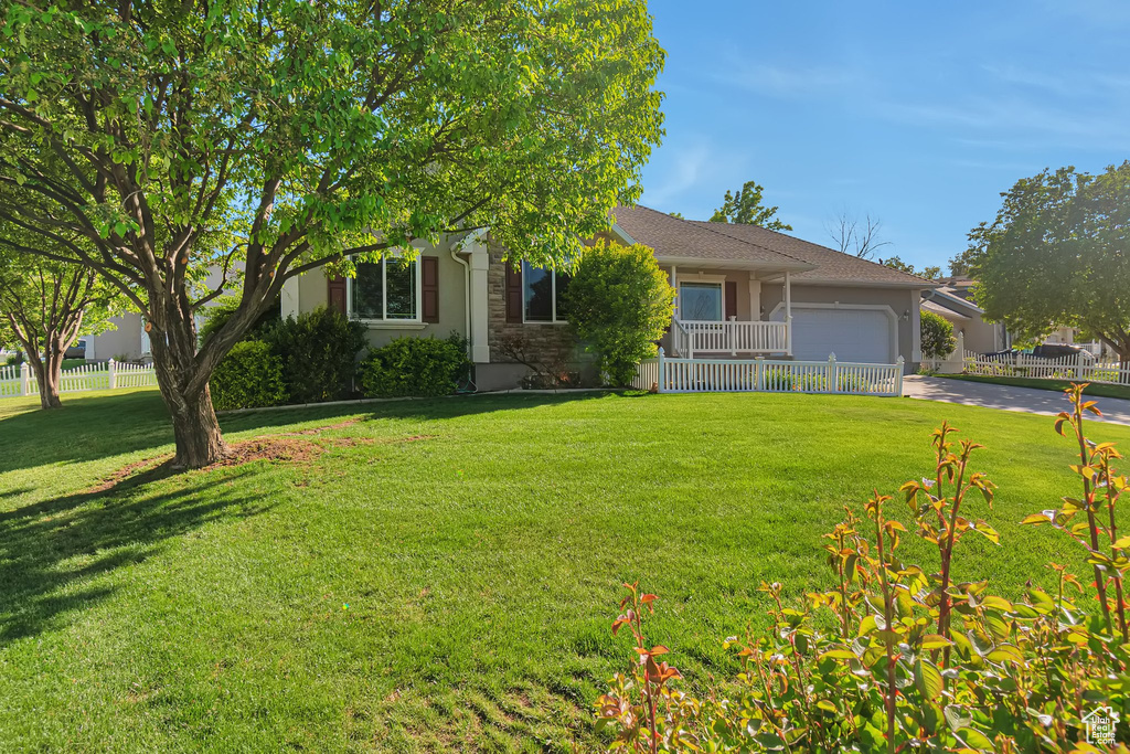 View of property hidden behind natural elements with an attached garage, stucco siding, and driveway