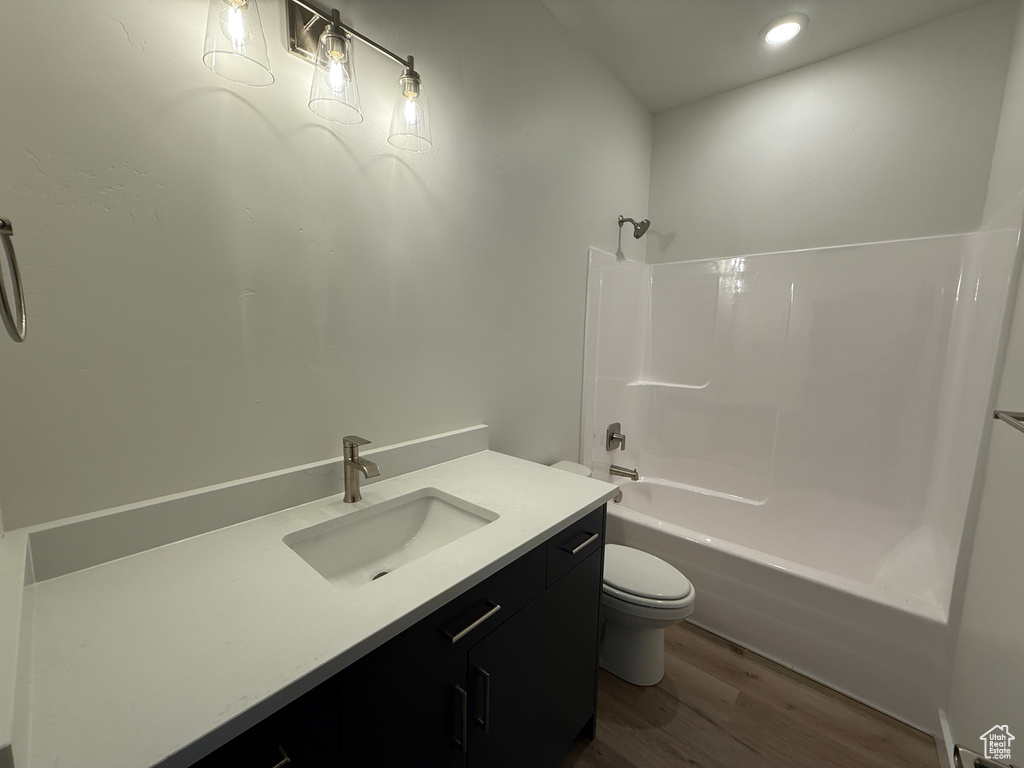 Bathroom with toilet, wood finished floors, vanity, shower / bath combination, and recessed lighting