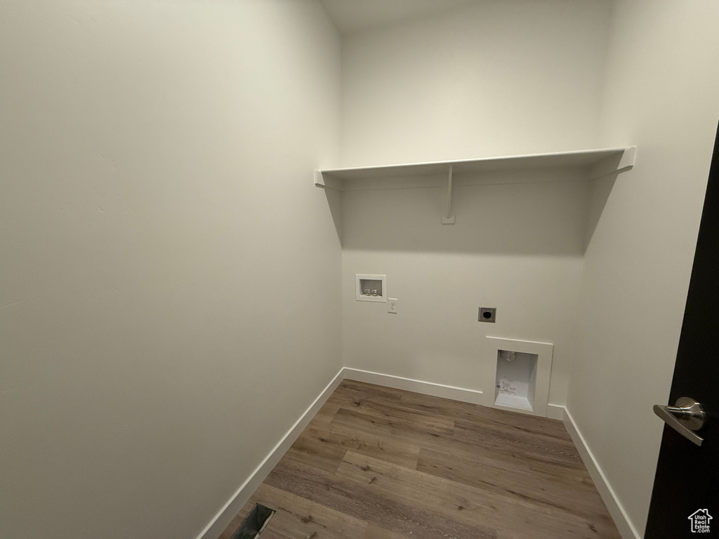 Washroom with hookup for a washing machine, electric dryer hookup, wood finished floors, and baseboards