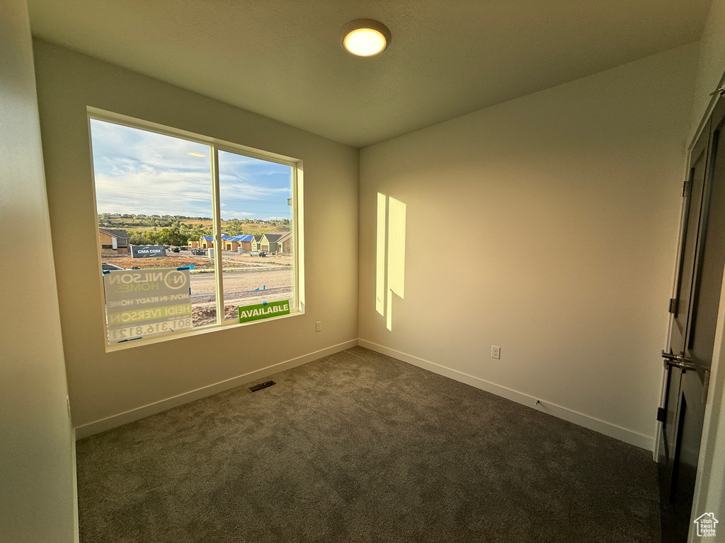 Unfurnished room featuring dark colored carpet and baseboards