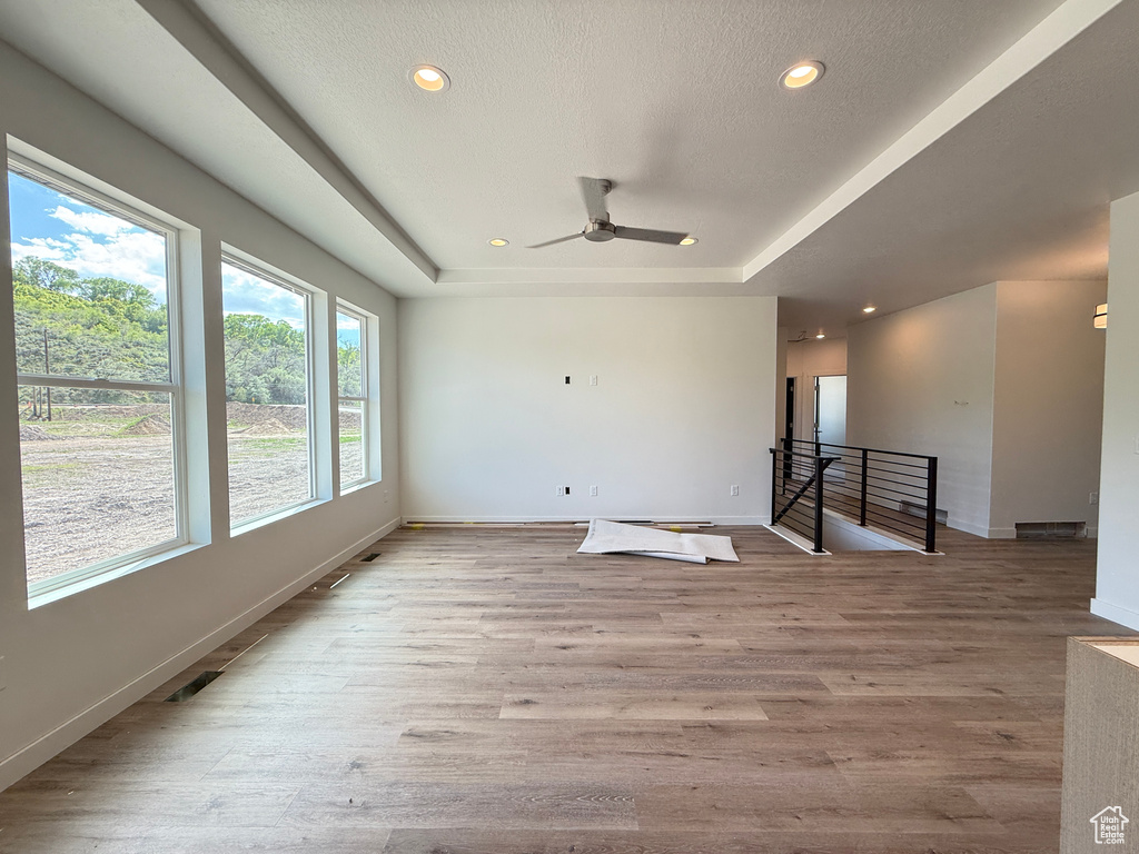 Empty room with baseboards, a raised ceiling, recessed lighting, a ceiling fan, and wood finished floors