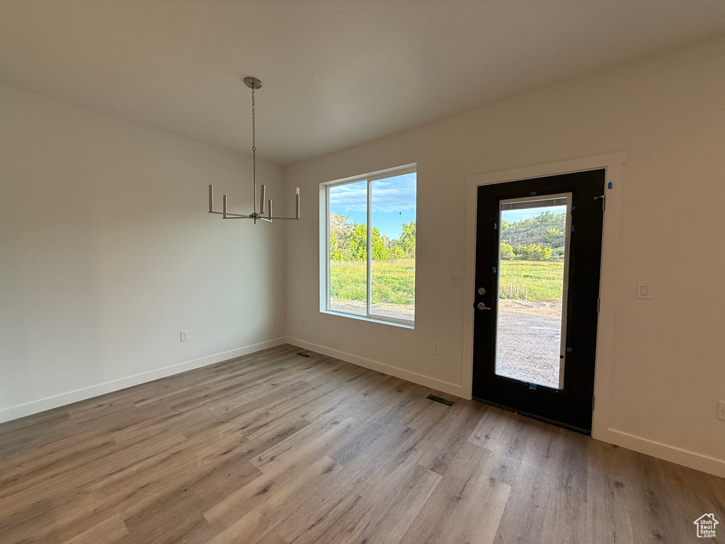 Unfurnished dining area with light wood-style flooring, baseboards, and a chandelier