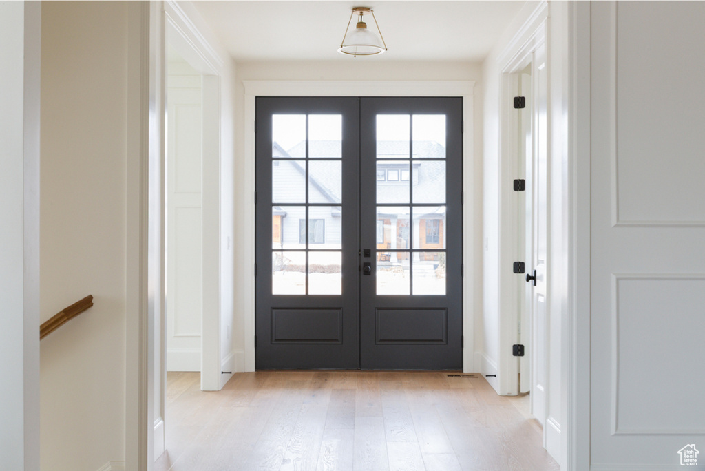Entryway with french doors, light wood finished floors, and baseboards