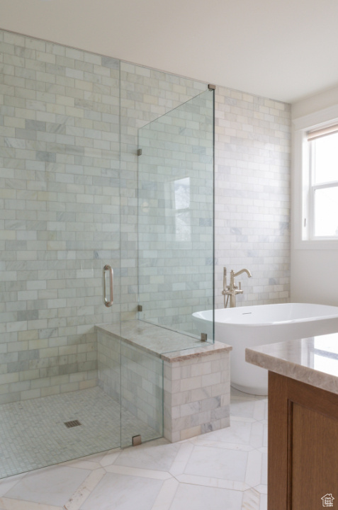 Full bath with a stall shower, a freestanding bath, tile walls, vanity, and tile patterned floors
