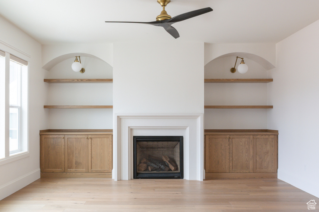 Unfurnished living room featuring a ceiling fan, light wood-style floors, and a fireplace