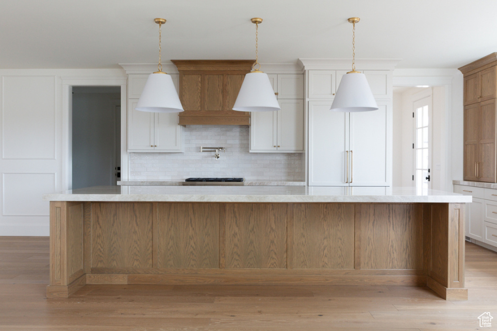 Kitchen with backsplash, light wood-type flooring, light countertops, and pendant lighting