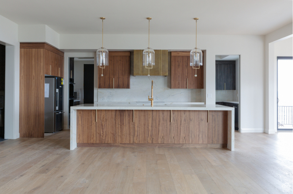 Kitchen featuring freestanding refrigerator, light countertops, and light wood finished floors