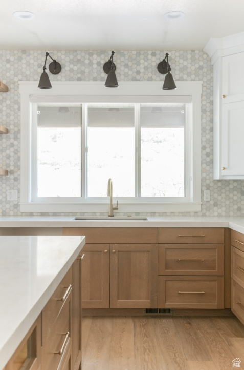 Kitchen with a sink, light countertops, light wood-type flooring, open shelves, and white cabinetry