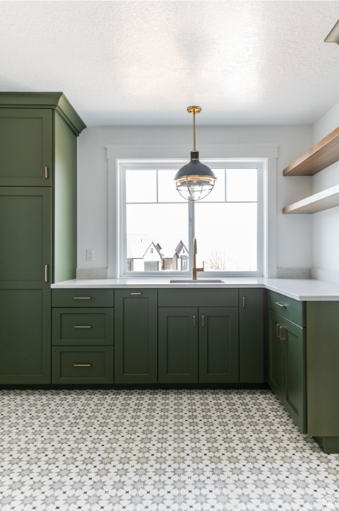 Kitchen with green cabinetry, a sink, open shelves, light countertops, and healthy amount of natural light