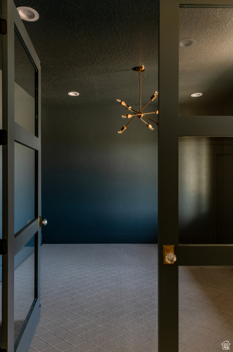 Carpeted spare room with a textured ceiling, a chandelier, and recessed lighting