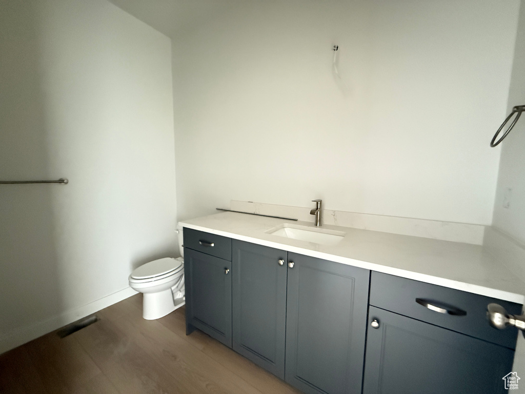 Bathroom with toilet, wood finished floors, vanity, and baseboards