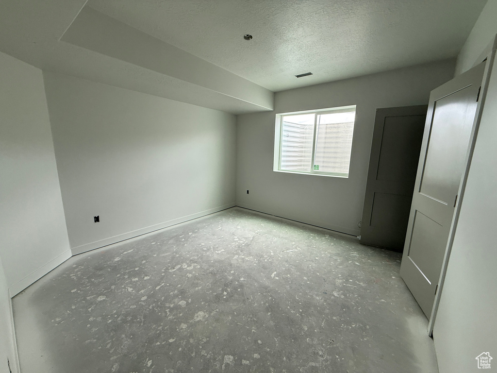 Unfurnished room with a textured ceiling and baseboards