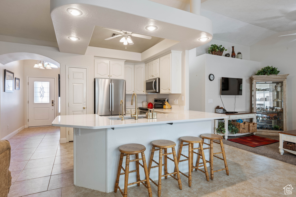 Kitchen with appliances with stainless steel finishes, ceiling fan, arched walkways, a peninsula, and a sink