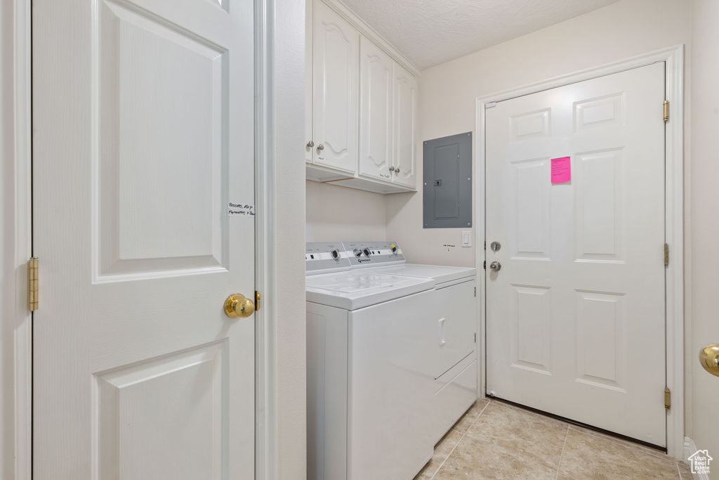 Laundry room with electric panel, independent washer and dryer, cabinet space, and light tile patterned flooring