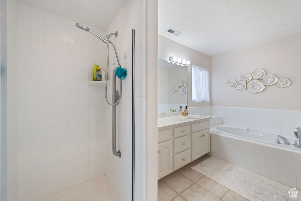 Full bathroom featuring tile patterned floors, a tile shower, a bath, and vanity