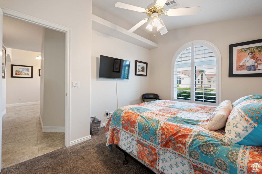 Carpeted bedroom with baseboards, a ceiling fan, and tile patterned flooring