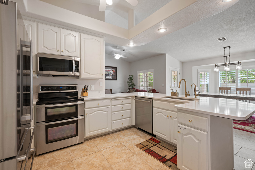 Kitchen with appliances with stainless steel finishes, ceiling fan, a sink, a peninsula, and recessed lighting