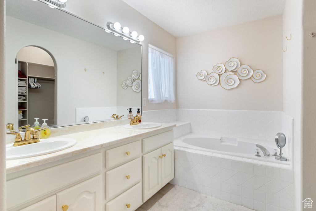 Bathroom featuring tile patterned flooring, a garden tub, double vanity, and a walk in closet