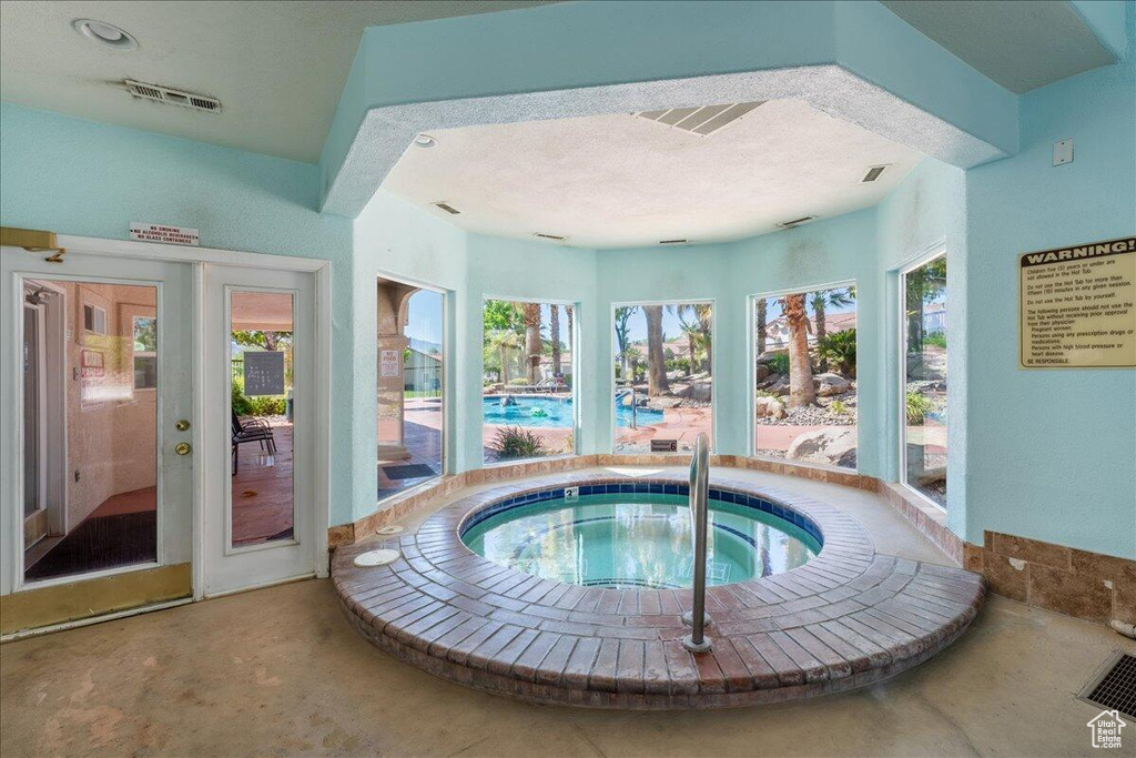 Indoor pool featuring an in-ground hot tub