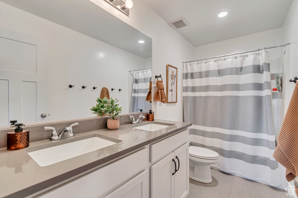 Full bathroom featuring toilet, double vanity, recessed lighting, and curtained shower