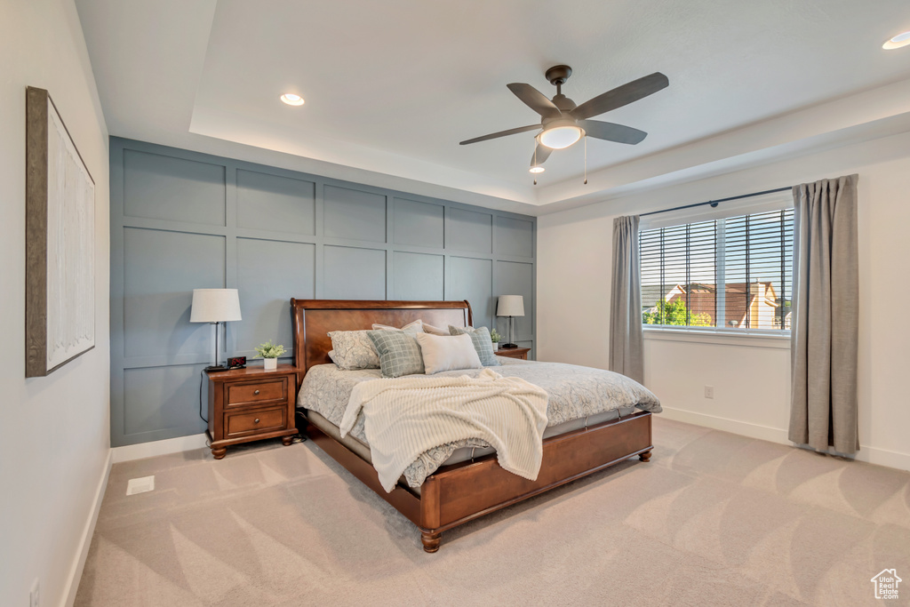 Bedroom with a tray ceiling, baseboards, light colored carpet, recessed lighting, and ceiling fan