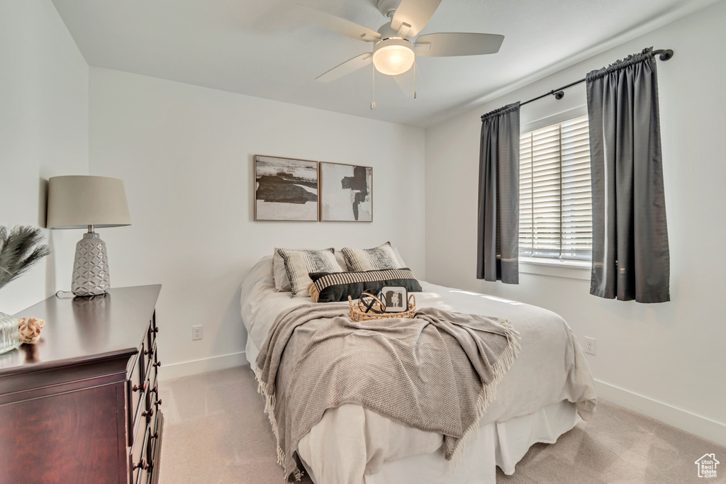 Bedroom featuring light carpet, baseboards, and ceiling fan
