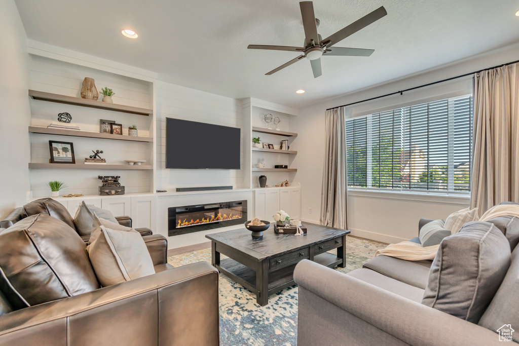 Living room with baseboards, ceiling fan, recessed lighting, a glass covered fireplace, and light carpet