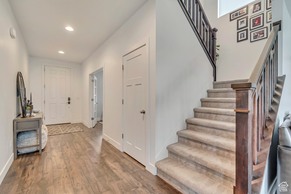 Entryway with stairs, recessed lighting, wood finished floors, and baseboards