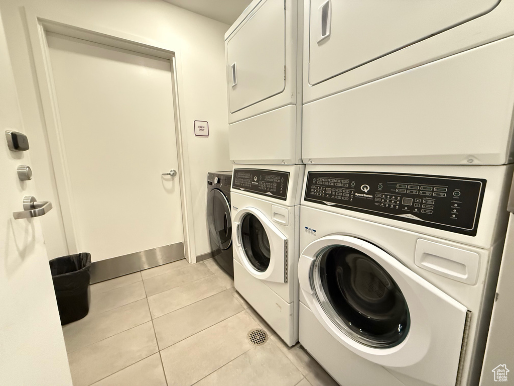 Clothes washing area with washer and dryer, light tile patterned flooring, and baseboards