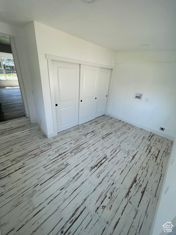Unfurnished bedroom with light wood-type flooring, baseboards, and a closet