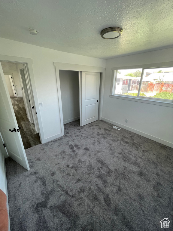 Unfurnished bedroom featuring baseboards, carpet floors, a closet, and a textured ceiling