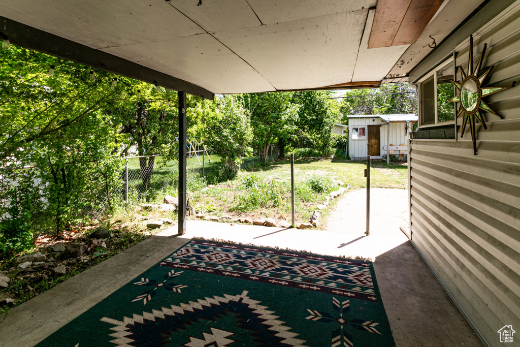 View of patio with a storage unit, fence, and an outdoor structure