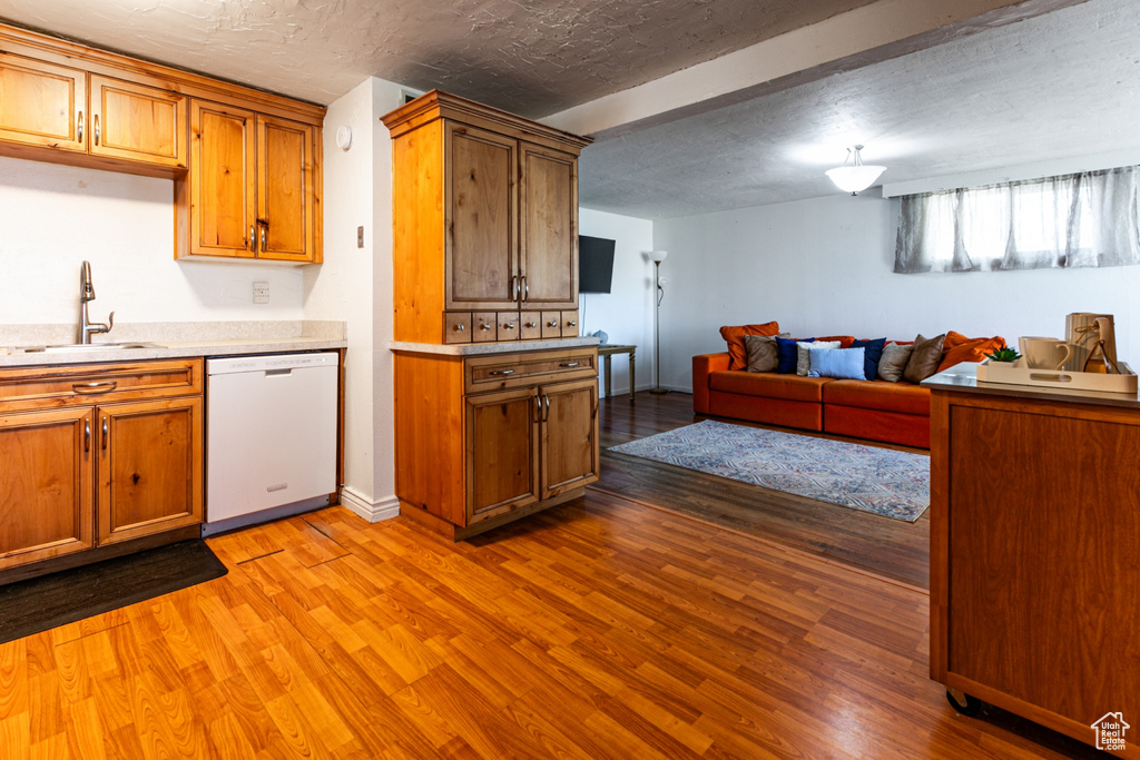 Kitchen with white dishwasher, a sink, and brown cabinetry