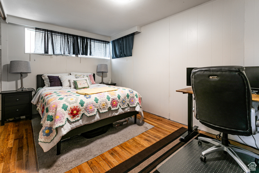 Bedroom featuring multiple windows, wood finished floors, and a desk